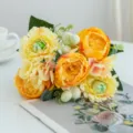 Close-up detail of vibrant artificial yellow and orange flower bouquet on clean white tabletop. - Yellow