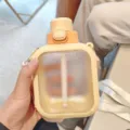 Vista dettagliata di borraccia piatta in plastica portatile con tracolla e cannuccia per uso. - Stile Piatto (JG2575) / 700ml / Giallo