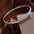 Gros plan détail du bracelet strassé à ressort argenté sur tissu satiné et boîte. - Ras du cou / Argent