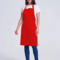 Vue détaillée de tablier de travail rouge avec poches pratiques et bretelles réglables. - Rouge