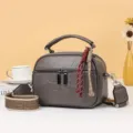 Detailansicht der Retro-Weichleder-Umhängetasche mit Reißverschlüssen und breitem Webgurt. - Grau