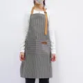 Black and white striped apron with brown straps, adjustable neck and front pocket variant. - Black