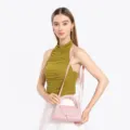 Close-up detail of the pink leather semi-circular handbag with metal lock and strap. - Pink