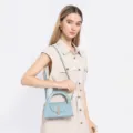 Detailed view of the light blue semi-circular crossbody bag with metal lock and handle. - Blue
