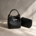 Vista detallada del lujoso bolso cubo de cuero negro con detalle de cierre metálico. - Negro