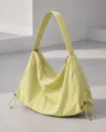 Detail shot of the minimalist yellow nylon hobo shoulder bag showing texture and hardware. - Yellow