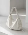 Detalle de bolso de hombro hobo de nailon minimalista, silueta suave y cordones ajustables. - Blanco Roto