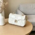 Bolso de hombro acolchado en cuero aceitado blanco con cadena dorada y cierre elegante. - Blanco