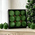 Detailansicht grüner beflockter Christbaumkugeln in schwarzer Geschenkbox und Weihnachtsbaum. - Grün (ASSNR89-44)
