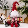 Christmas gnome doll with striped knitted hat and long dangling legs sitting on a red vintage car. - Red