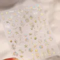 Nahaufnahme von holografischen Gold-Meeres-Nagelstickern mit Meerjungfrauenschwänzen - M-1464 Ozeanstern-Goldprägung Und Glasbruch