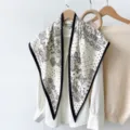 Detailopname van een retro zwart-witte paisley print driehoekige sjaal hangend aan een hanger. - RY-01