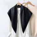 Detailed view of a stylish black polka dot silk triangle scarf hanging with white shirt. - RY-14