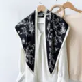 Detail shot of a vintage black and white floral print triangular silk scarf, elegantly draped. - RY-18