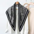 Close-up detail of the vintage black and white paisley silk scarf draped over a white blouse. - RY-35