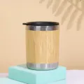 Stainless steel coffee mug detail shot featuring a natural bamboo shell and black lid. - 350 ml / No Handle