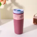 Close-up detail of a pink stainless steel insulated travel coffee mug with a purple lid on a clean table. - 350ml / Rose