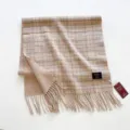 Vista detallada de una bufanda de lana a cuadros beige retro con flecos y marca tejida. - Cuadros Beige / 55x200cm
