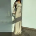 Detail shot of elegant long-sleeve satin maxi dress in champagne, featuring fitted waist line. - S / Apricot