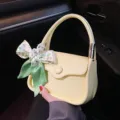 Elegante hellgelbe Mini-Satteltasche mit grünem Blumenseidenschal am Griff gebunden - Weiß