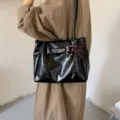 Elegante schwarze Tragetasche aus weichem Leder mit Plissee-Design und Schmetterlingsanhänger - Mit Schmetterlingsanhänger / Schwarz
