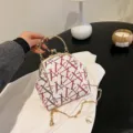 Elegant white sequined shell bag featuring red geometric patterns and a gold chain strap - Red