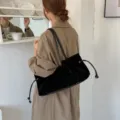 Κομψή μαύρη τσάντα ώμου από συνθετικό σουέτ με κορδόνι φορεμένη με καμπαρντίνα - Μαύρο