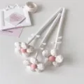 Close-up of three elegant fabric flower-topped gel pens with pink polka dot petals - 1PC / White
