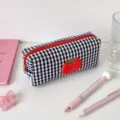Zoom sur une trousse à carreaux noir et blanc avec un écusson de tomate rouge brodé - Style Long / Noir