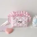 Détail d'une trousse de maquillage rose matelassée avec volants et étiquette hisocute. - Rose