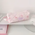 Detail view of a pink quilted pencil case featuring bow patterns and Hisocute brand label - Pink