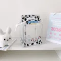 Close-up view of a clear PVC milk carton storage bag with black cow print for plush doll display - Black