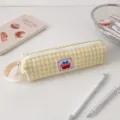 Primo piano di astuccio a quadretti gialli con toppa ciliegia su tavolo bianco - Quadretti Gialli