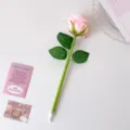 Close-up of a realistic pink artificial rose pen on a white surface with decorative props. - Pink