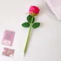 Detail view of a creative pink rose-shaped ballpoint pen on a clean white desk background - Rose Red