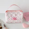 Close-up van een roze geruite gewatteerde cosmetische tas met handvat en strikpatronen - Roze
