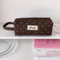 Gros plan détaillé d'une trousse matelassée marron avec pois roses et motifs de cœur - Long Marron (avec poignée)