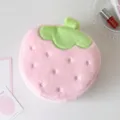 Detail view of a cute plush strawberry-shaped makeup bag with soft pink fabric and green leaves - Pink Strawberry (Plush)