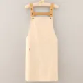 Minimalist beige cotton apron with adjustable brown straps and front pocket for cooking. - Beige