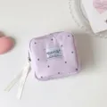 Primer plano de un neceser de tela morado con lunares y una elegante cinta blanca - Lunares morados