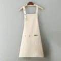 Delantal de trabajo de lona en color beige con tirantes cruzados ajustables y bolsillos. - Beige