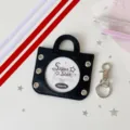 Detailed view of black mini handbag badge protection cover with clear window and metal grommets - Including Four Ribbons in Two Colors / Black