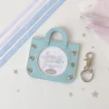 Close-up of a light blue coquette style badge display bag with a circular window. - Including Four Ribbons in Two Colors / Blue