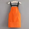 Orange short kitchen apron with black straps and front pockets for home cooking and dining work. - Strap Style Orange