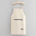 Waterproof kitchen apron with pocket and adjustable straps in solid beige color for cooking. - Off White