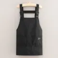 Black canvas work apron with adjustable straps and front pockets for kitchen and cooking use - Black