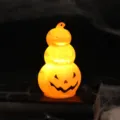 Glowing stack of three Halloween pumpkin lanterns with warm orange light on dark background - Pumpkin