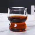 Verre transparent au design étagé contenant une boisson ambrée pour un usage quotidien. - Blanc