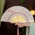 Éventail pliant de style traditionnel chinois avec motifs floraux et pompon rose. - Cerise Rose Pluie de Printemps/Poignée Rose