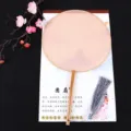 Detail shot of traditional Chinese round fan with wooden handle and elegant grey tassel. - Beech Wood Handle Pink